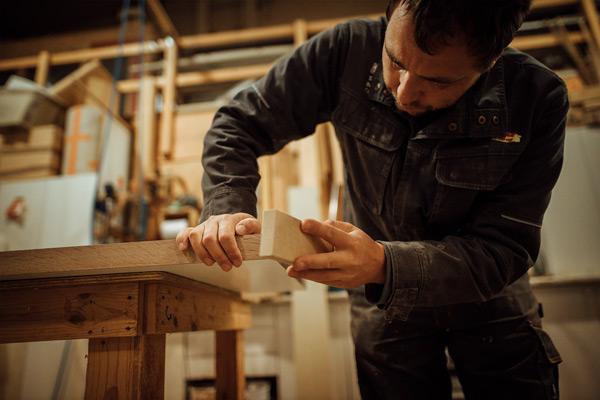 Homme qui ponce une planche de bois